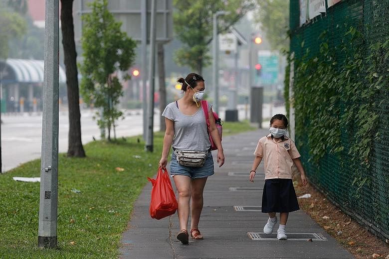 A woman and child heading home in Pasir Ris Drive 6 at 3.30pm yesterday. Most schools have minimised their outdoor activities. Heavy rain and haze at about 6pm yesterday at Jubilee Bridge in southern Singapore. For most of the school day yesterday, t