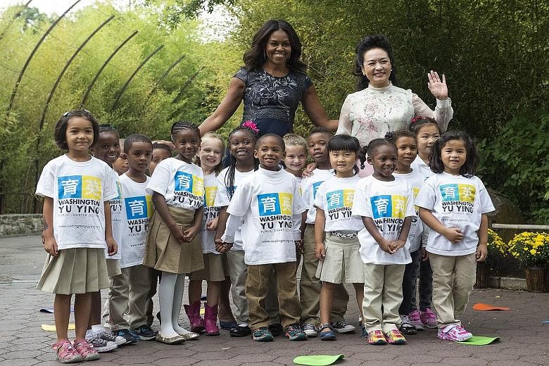 US First Lady Michelle Obama and China's First Lady Peng Liyuan with students from Washington Yu Ying Public Charter School after their performance at the Smithsonian's National Zoo last Friday in Washington, DC. Due to a projected faster rise in the