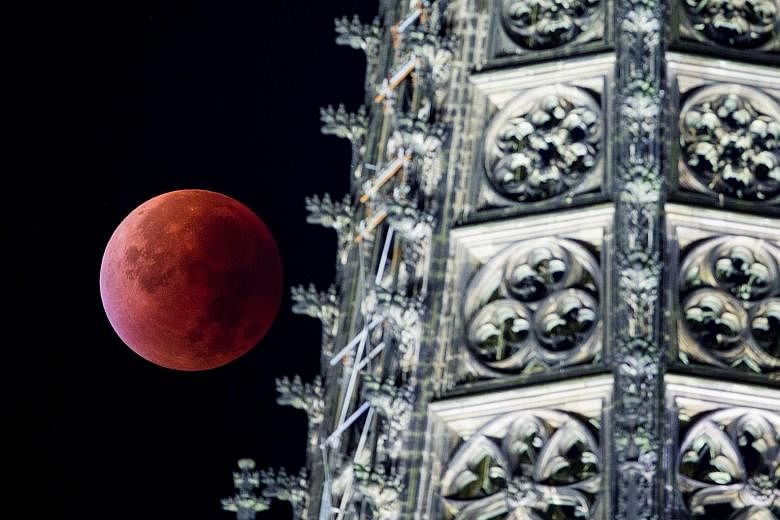 The supermoon (top) appearing above Cologne cathedral in Germany yesterday. (Above) In Cape Town, South Africa, Earth's shadow can be seen partially covering the Moon.