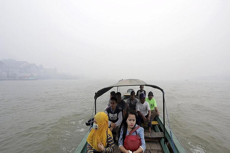 Residents crossing the haze-shrouded Musi River in Palembang, South Sumatra province, yesterday. Indonesia's Coordinating Minister for Political, Legal and Security Affairs Luhut Panjaitan and Defence Minister Ryamizard Ryacudu gave the assurance tha