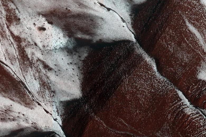 A handout image, made available by Nasa on Sept 27, shows dark, narrow, 100m- long streaks flowing downhill on Mars. Scientists detected hydrated salts on these slopes at Horowitz crater, corroborating their original hypothesis that the streaks are f