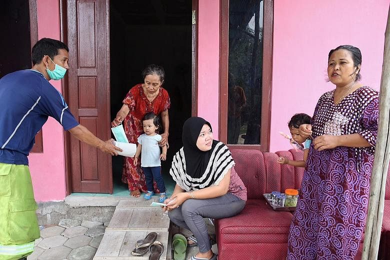 An official giving masks to Kapuas regency residents (from left) Mastika, her granddaughter Mutiara Lestari, neighbour Masita and her daughter Amelia Putri, and Mutiara's mother Mahrita.
