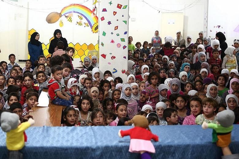 Syrian children who have lost one or both of their parents in the conflict watching a puppet show during a party organised by an NGO in the rebel-held district of Douma, east of Damascus, on Monday. Douma is part of the rebel-held Eastern Ghouta area