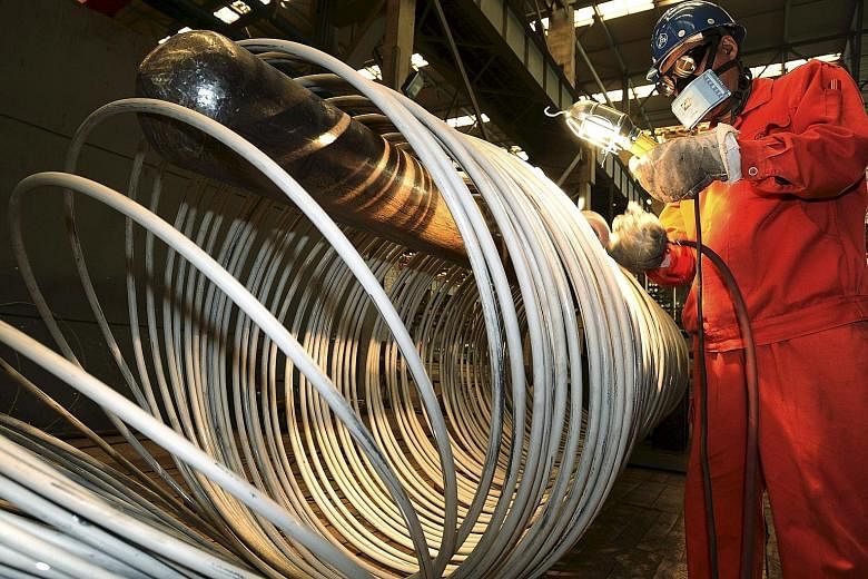 A worker polishing steel coils at a factory in Dalian, Liaoning province, China. Surveys of China's factory and services sectors showed the world's second-largest economy may be cooling more rapidly than earlier thought, with deeper job cuts.