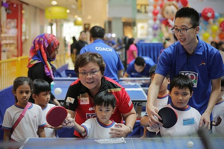 Singapore Table Tennis Association (STTA) president Ellen Lee teaching the game to a group of pre-school children at the STTA-PAP Community Foundation Table Tennis Carnival yesterday. National paddlers Li Hu and Zhou Yihan were also present at the ev