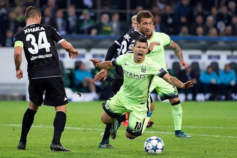 Manchester City striker Sergio Aguero (centre) tumbling in the penalty box under a challenge by Borussia Moenchengladbach's Fabian Johnson in the final minute of the match in Germany. The Argentinian then coolly slotted home the penalty kick to win t