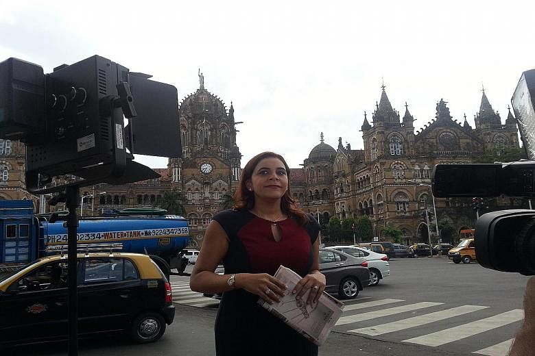 Karishma Vaswani on the streets of Mumbai, where busy modern traffic swirls around grand old buildings.