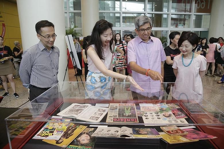 Dr Yaacob Ibrahim viewing a collection at the display to mark the NLB's 20th anniversary at the National Library Building yesterday, with (from left) NLB chairman Chan Heng Kee, assistant director for content and services Alicia Yeo, and chief execut