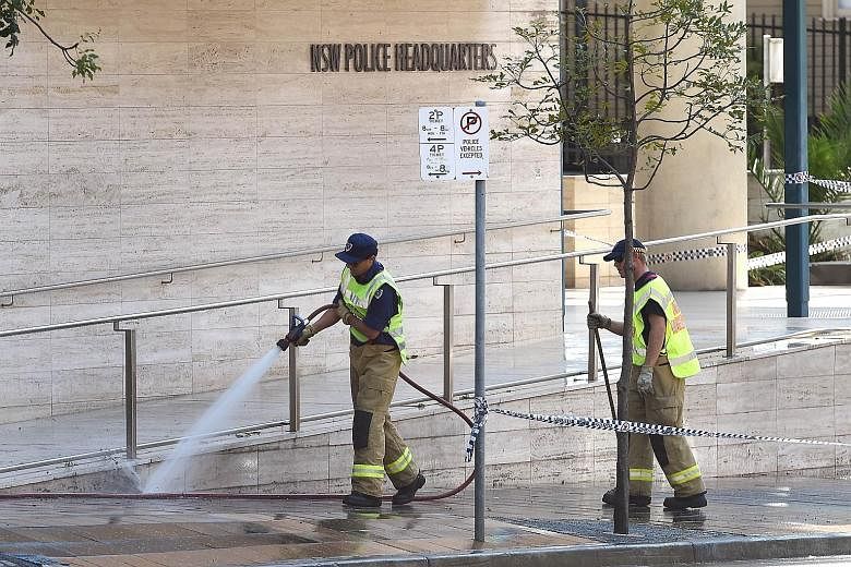 A fireman yesterday hosing down the scene where a 15-year-old boy shot dead a civilian police employee last Friday, before being gunned down by police, in Sydney.