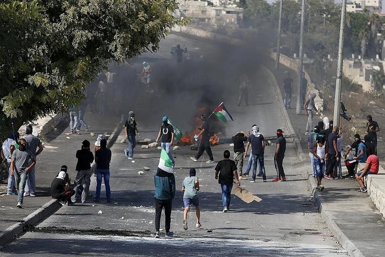 Palestinians gathering near a burning barricade during clashes with Israeli security forces in the East Jerusalem neighbourhood of Issawiya on Sunday.