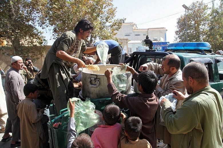 Residents receiving food distributed by police in the city of Kunduz, Afghanistan, on Sunday. Afghan security forces said yesterday they had reclaimed most of the city from the Taleban, allowing residents to leave their homes to buy food for the firs