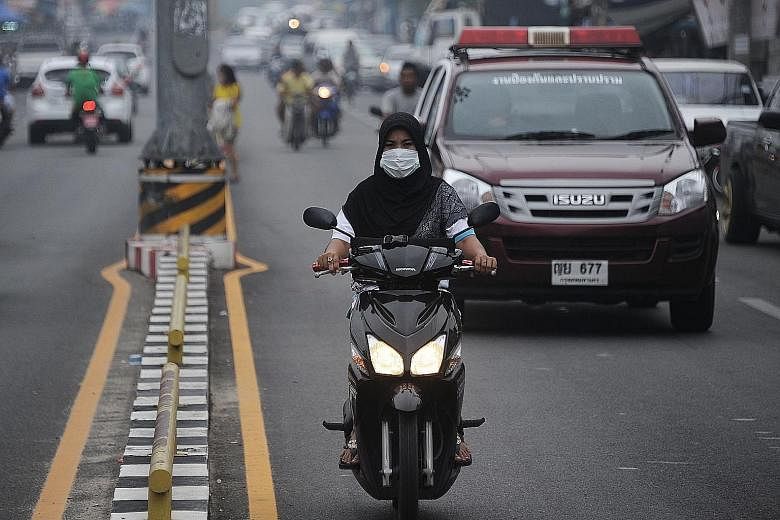 A motorcyclist, with face mask on, riding through haze-hit Narathiwat in southern Thailand on Monday. Thick haze blamed on forest fires in Indonesia has started to affect Thailand's southern provinces.