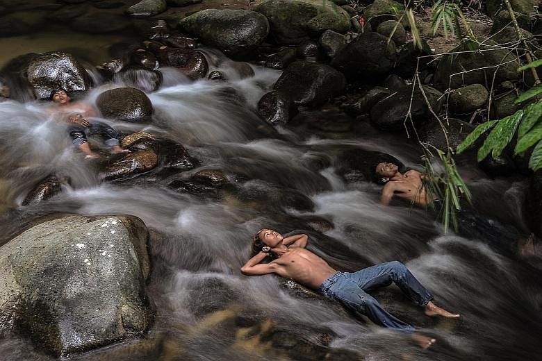 Young people in Malaysia getting some respite from the haze by cooling off in a river as schools remained closed due to hazy conditions in Hulu Langat, Selangor, yesterday. Forest and land fires raging in Sumatra and Kalimantan have intensified over 