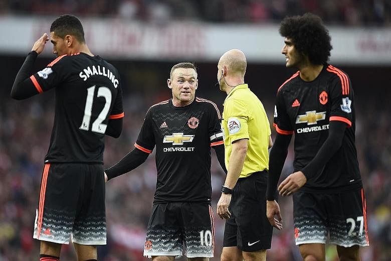 A flustered Manchester United skipper Wayne Rooney (centre) talking to referee Anthony Taylor. His team were ruthlessly exposed by Arsenal in the 3-0 defeat.