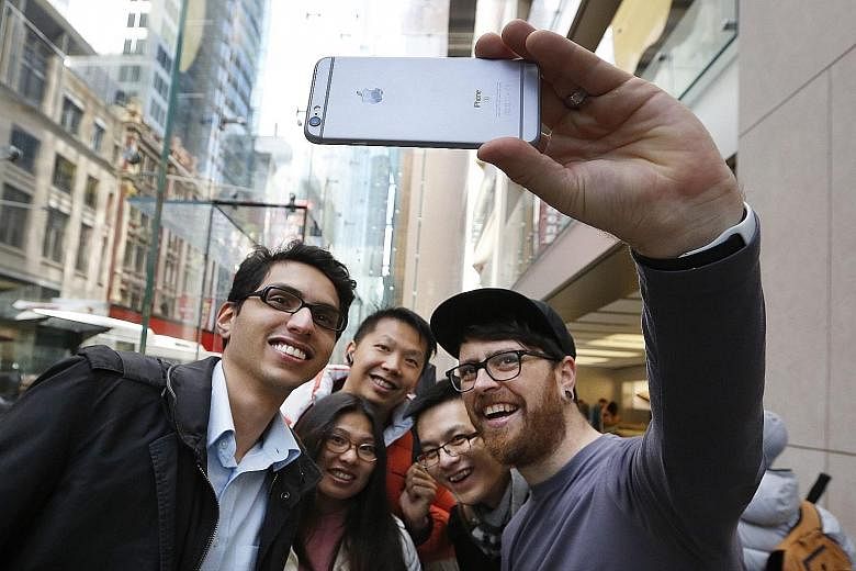 An Apple employee using an iPhone 6s to take a wefie with people queueing inside its Sydney store. Apple holds US$181.1 billion (S$258 billion) offshore, more than any other US firm, and would owe US$59.2 billion in US taxes if it tried to return the