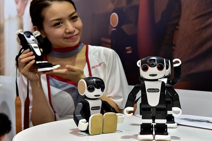 LEFT: A woman playing ping pong with a robot created by Japan's Omron. ABOVE: Sharp's Robohon, designed by robot creator Tomotaka Takahashi, can speak, dance and make phone calls.