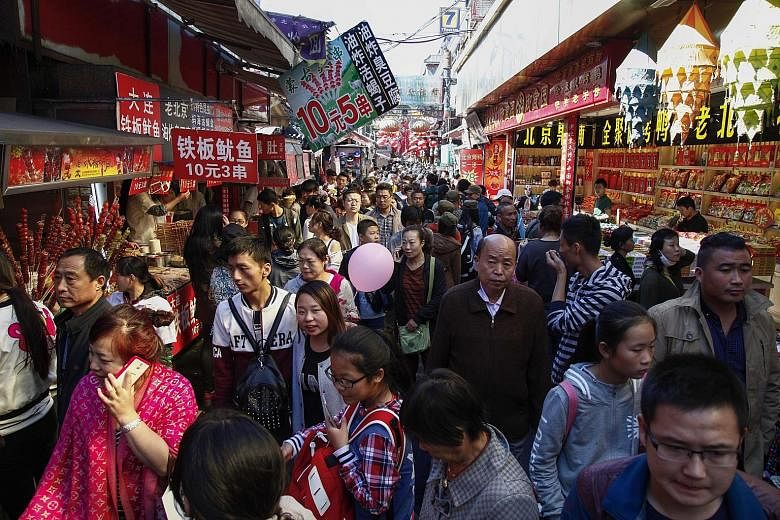 Tourists thronging a busy food street in the Wangfujing shopping and tourist district in Beijing on Oct 1. Despite a rocky economy, many cities and provinces across China reported higher tourist numbers and receipts.