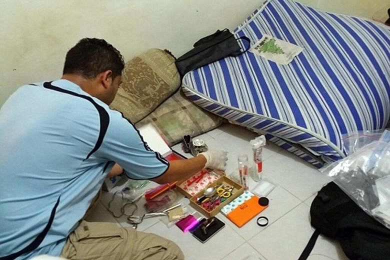 A CNB officer examining the haul, which includes about 3kg of heroin, 495g of Ice, 326 Ectasy tablets, 64 Erimin-5 tablets, 42g of cannabis and a small amount of new psychoactive substances.