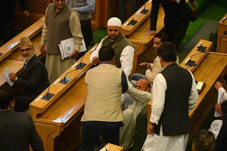 Opposition Muslim member Abdul Rashid (centre) falls after being punched and shoved by BJP legislators in the Jammu and Kashmir state assembly on Thursday. He had served beef at a party in protest over a ban on killing and eating cows in India's only