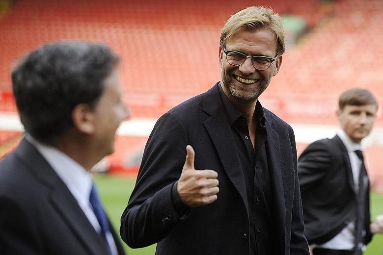 Juergen Klopp (centre) gives the thumbs up as he walks near Liverpool chairman Tom Werner (foreground left) during his presentation at Anfield on Friday.