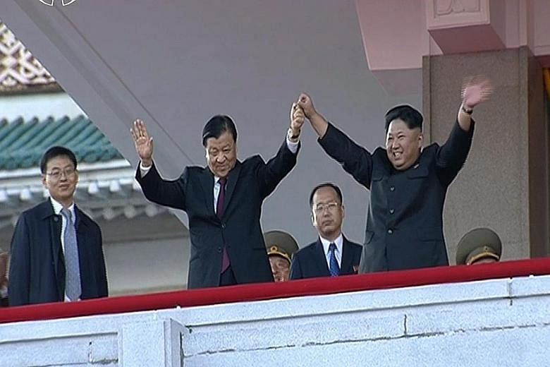 North Korean leader Kim Jong Un (right) holding hands with senior Chinese Communist Party official Liu Yunshan during the massive military parade in Pyongyang yesterday.