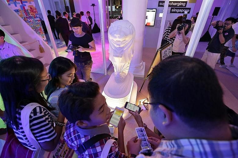 Visitors at the Festival of Tech, which runs till next Sunday, trying to strike up a conversation with a mini Merlion through mobile texting.