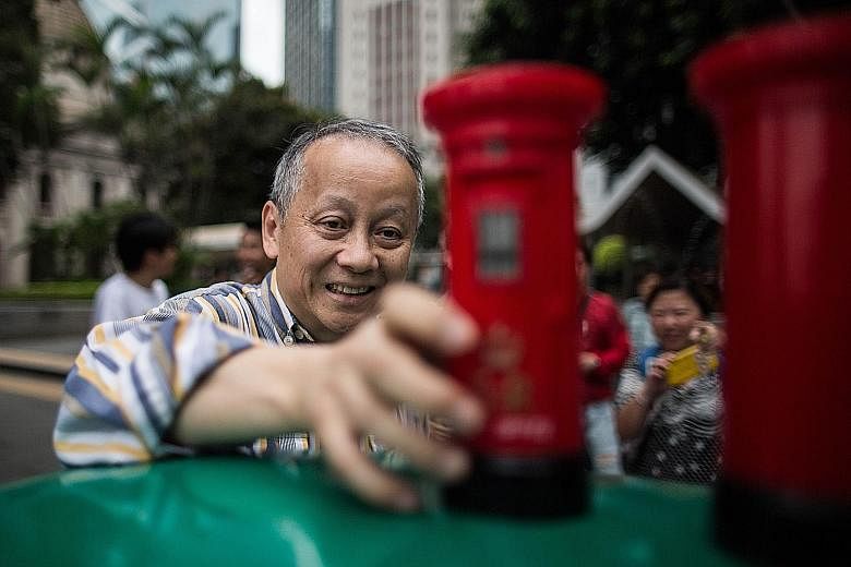 A man placing a toy British colonial-era postbox souvenir on top of a postbox from the colonial period during a protest in the Central district of Hong Kong on Saturday. Hong Kong's red colonial postboxes were painted green after the city reverted to