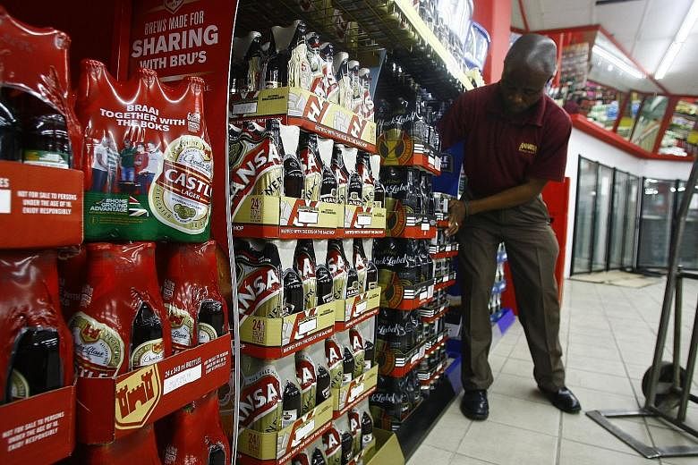 An employee restocking SABMiller beer products at a Durban City Bottle store in Durban, South Africa. Anheuser-Busch InBev will pay £44 a share in cash for a majority of the shares in its nearest competitor.