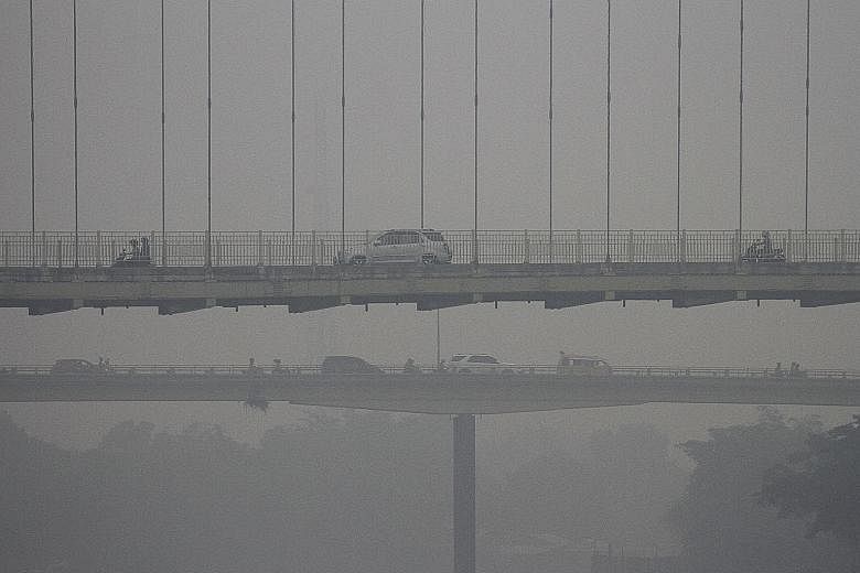 Left: The Siak Bridge in Pekanbaru, Riau, shrouded in haze on Sunday. Fires that cause haze are often started to clear land for farming or to plant oil palm crops.