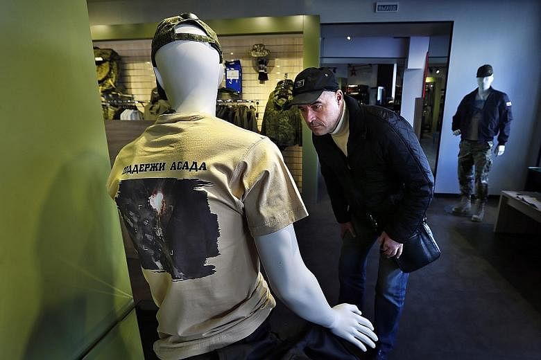 A man checking out a T-shirt bearing a photo of an aerial view of Russian air strikes in Syria, with the words "Support Assad", at a Russian Army Store in downtown Moscow yesterday. Turkey had earlier this month complained about two violations of its