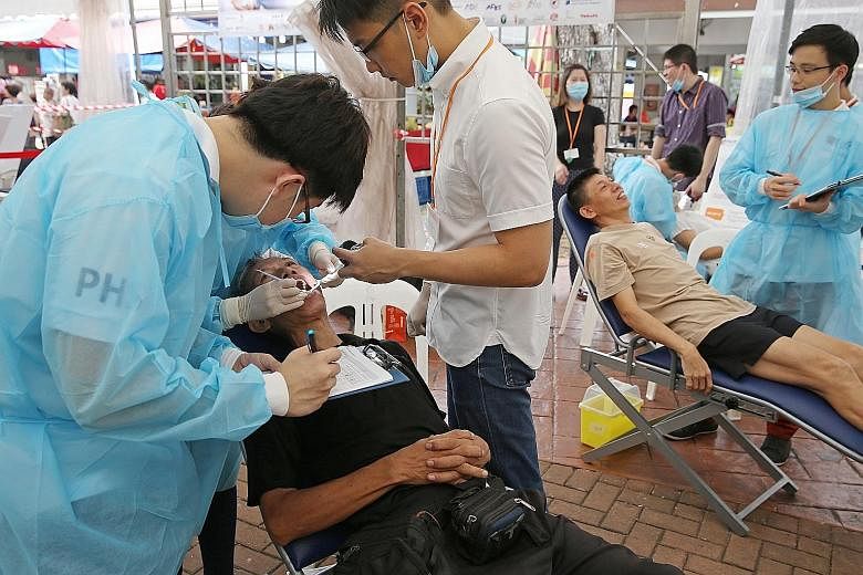 Members of the public getting free oral health checks by NUS dentistry students and dental officers at the Public Health Service event in Clementi yesterday. Dental checks are being offered at the event for the first time.