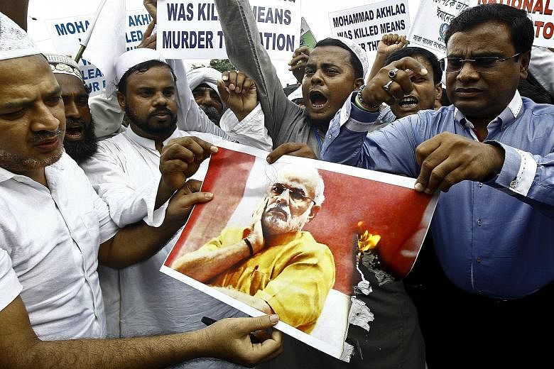 Demonstrators burning a portrait of PM Narendra Modi during a protest in Kolkata, India, on Wednesday. In his response to the murder of a Muslim man over rumours he ate beef, Mr Modi said the federal government had little role in the incident. Many i