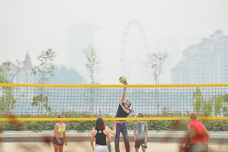 People playing volleyball at 4pm yesterday at the Singapore Sports Hub. The 24-hour PSI entered the unhealthy range in the afternoon.