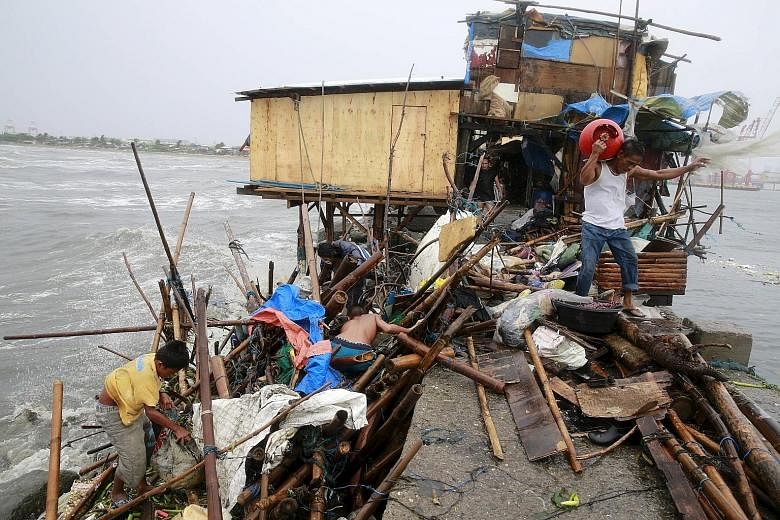 A family that lives along the coast of Manila Bay searching for salvageable items after their house was damaged by strong winds brought by Typhoon Koppu yesterday. At least eight people are missing, and a 14-year-old boy was killed when a tree fell o