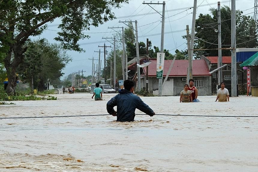 A resident holding onto a rope as he negotiates a current along a highway submerged by flood waters in Santa Rosa town, Nueva Ecija province, north of the Philippine capital Manila yesterday, a day after Typhoon Koppu hit Aurora province. Residents o