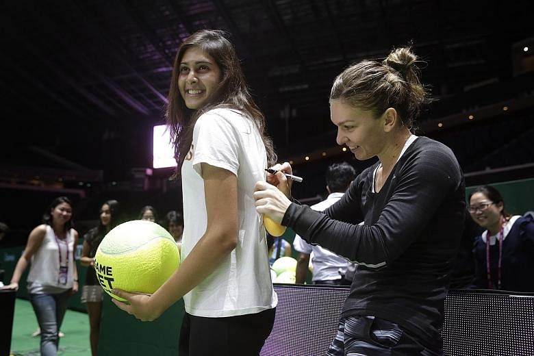 Simona Halep, who beat Serena Williams in the WTA Finals group stage last year, signs a fan's shirt at the Indoor Stadium yesterday.
