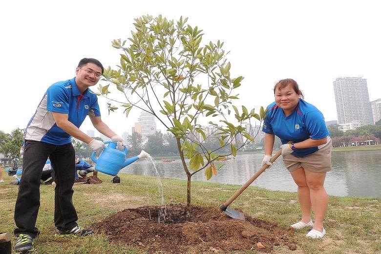 (Top) Standard Chartered staff with senior citizens at the bank's annual Silver Linings Carnival. This year's event next month will involve more than 1,000 staff volunteers. (Above) Singapore Pools staff planting trees on Oct 16 to support the Garden