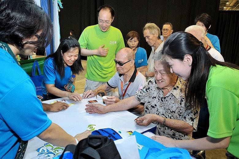 (Top) Standard Chartered staff with senior citizens at the bank's annual Silver Linings Carnival. This year's event next month will involve more than 1,000 staff volunteers. (Above) Singapore Pools staff planting trees on Oct 16 to support the Garden
