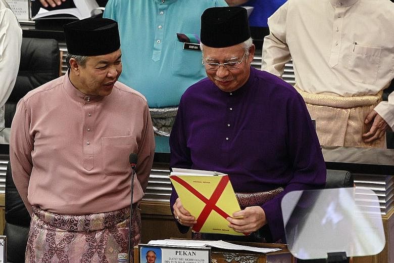 Malaysian Prime Minister Najib Razak holding the Budget draft as he spoke to DPM Ahmad Zahid Hamidi before addressing the MPs at Parliament House in Kuala Lumpur yesterday.