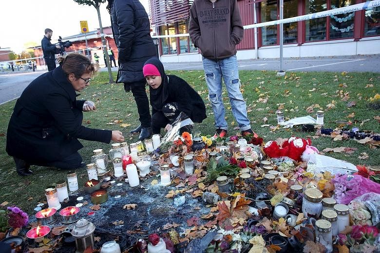 People lighting candles yesterday outside the Kronan School in Trollhattan, an industrial town in western Sweden with a large immigrant population. In Thursday's attack, the 21-year-old masked swordsman (above, right) walked through the school, stabb