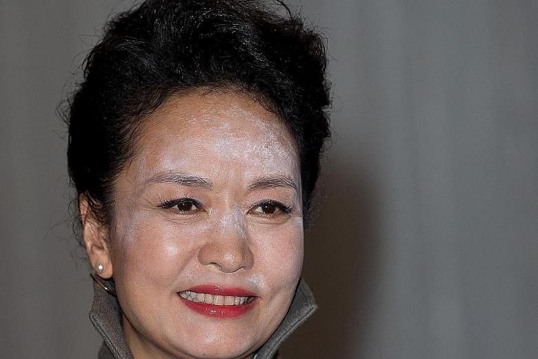Above: Photos of Ms Peng Liyuan at a reception hosted by the Lord Mayor of London show a heavy dusting of white powder on her forehead and nose. Left: Ms Peng, wearing a "dignified and graceful" blue silk coat dress, arriving with Queen Elizabeth at 