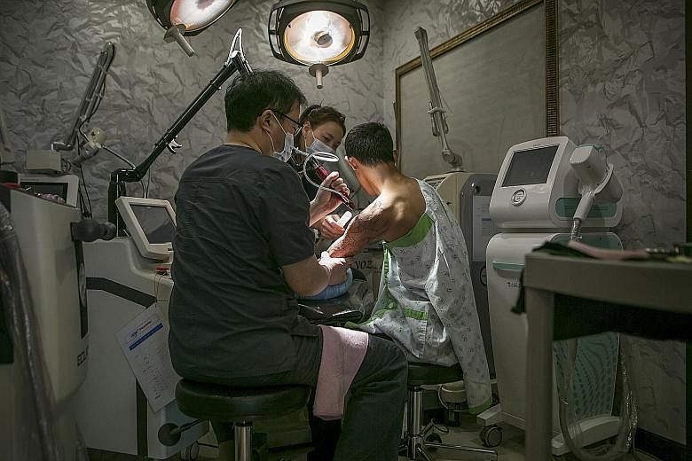 Dr Hong Jeong Geun using a laser to remove a tattoo from the arm of a North Korean defector at a clinic in Seoul.