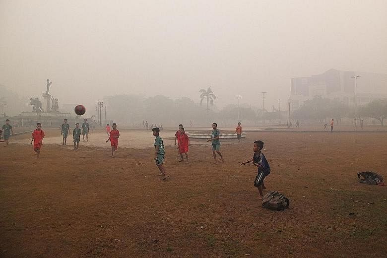 Left: Children playing football at a Bundaran Besar field yesterday morning when the PSI level was around 1,500 in Palangkaraya, Central Kalimantan. Below: People at VivoCity in Singapore enjoying the outdoors at 5pm, when the 24-hour PSI reading was