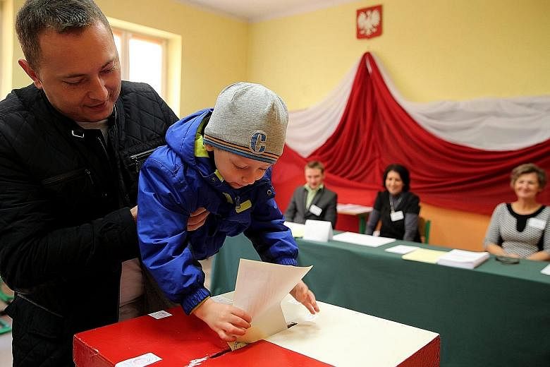 A man letting his child drop his vote in a ballot box at a polling station in Przecieszyn, south Poland, yesterday.