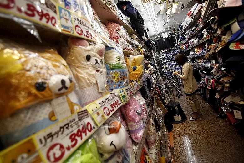 A shopper at a discount store in a Tokyo shopping district. The Bank of Japan's aggressive intervention has been central to Premier Shinzo Abe's economic policies, but events have conspired to blunt its impact, such as the sales tax increase last yea