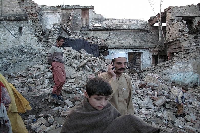 Residents making their way past the rubble of a house in Mingora in Swat district, Pakistan, after it was damaged by an earthquake yesterday. The 7.5-magnitude quake struck Afghanistan's Hindu Kush region and was felt throughout much of South Asia, k