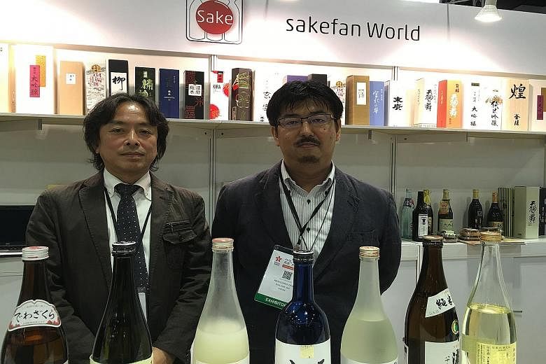 Sakefan World developers Kazuto Tsuchida (left) and Kenichiro Oka with bottles of sake listed in their app.