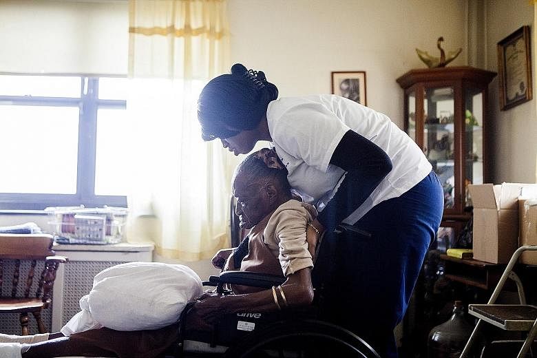 Home health aide Alicia Joseph helps dementia patient Naomi Wallace at her New York home. End-of-life costs for dementia are more expensive than for heart disease or cancer.