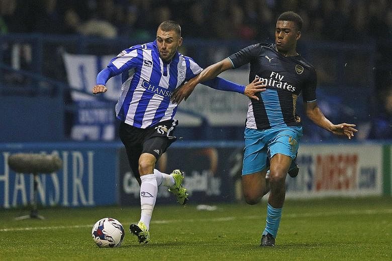 Sheffield Wednesday's Jack Hunt (left) trying to shrug off Arsenal's Alex Iwobi at Hillsborough on Tuesday. "It was a bad night at the office," said Arsene Wenger of the 0-3 League Cup loss.