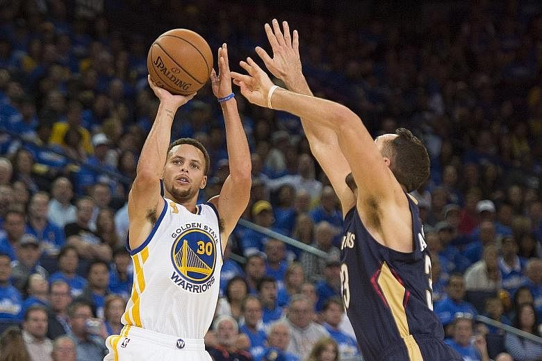 Golden State guard Stephen Curry getting in a shot despite the close attention of New Orleans forward Ryan Anderson. The NBA title holders won 111-95 at the Oracle Arena in Oakland.